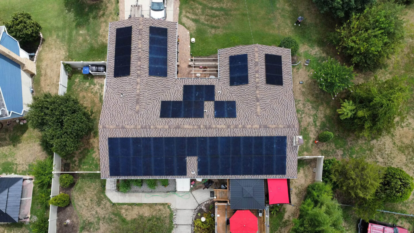 Aerial perspective of a large residential property featuring several solar panels installed on the roof.