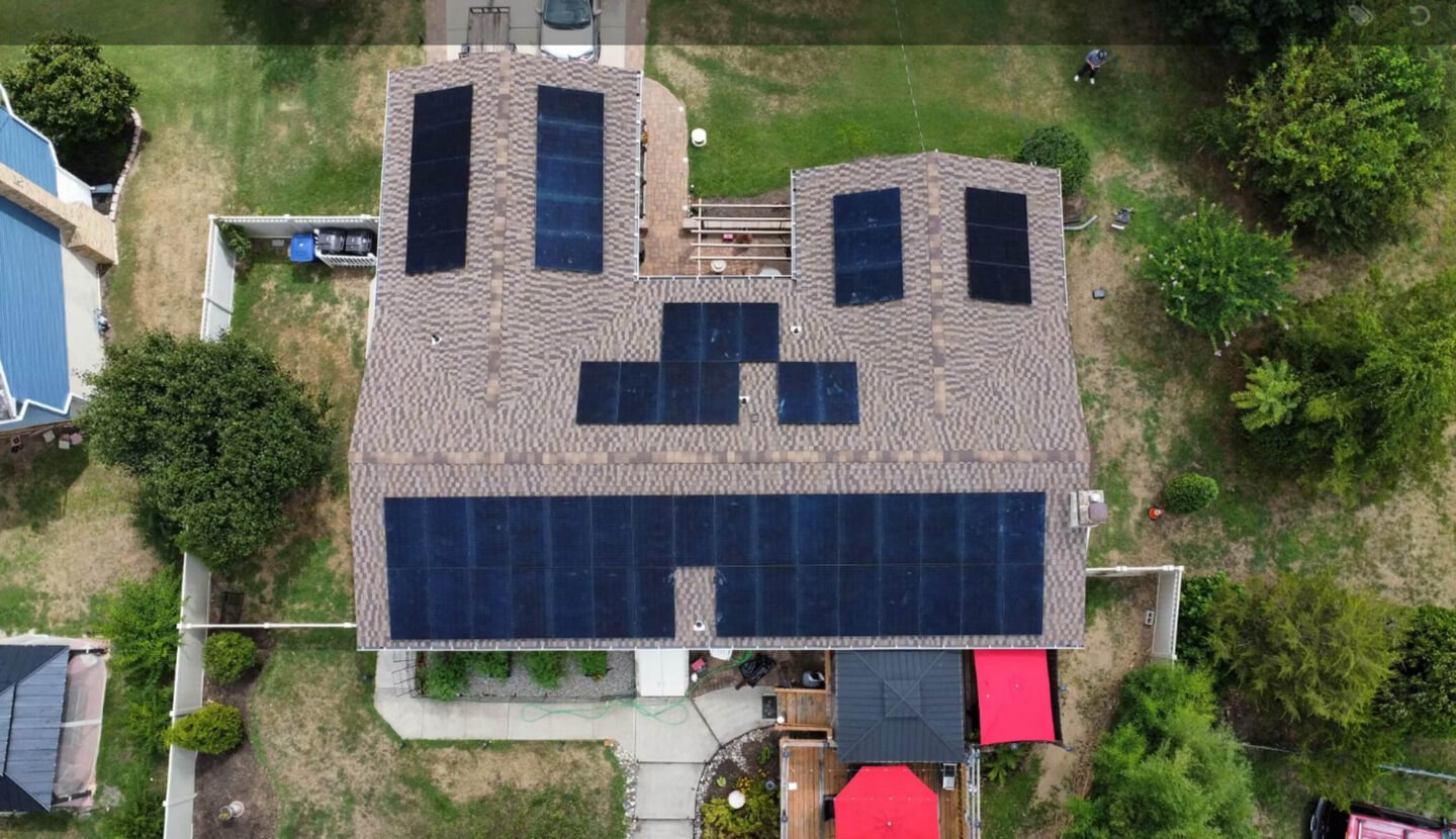 Aerial view of a large home featuring multiple solar panels installed across the roof.