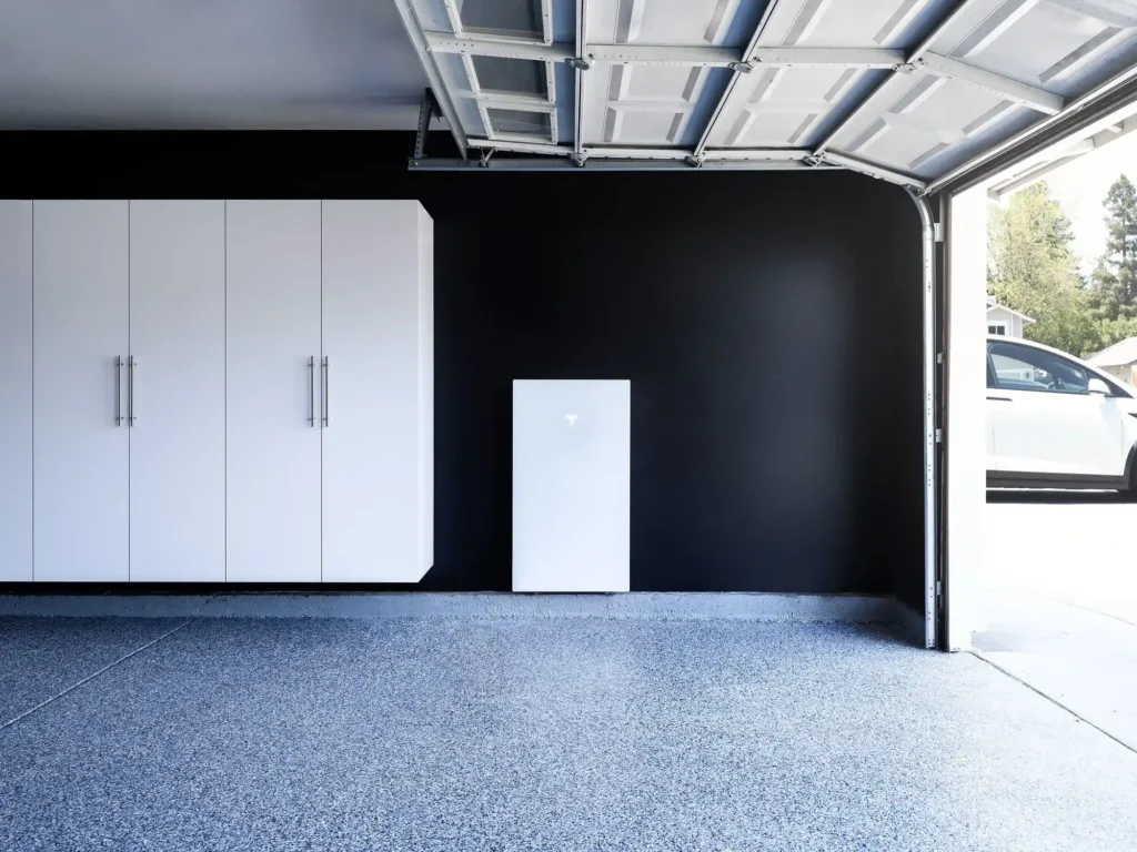 Minimalist garage with a black wall and white cabinets on the left. A small white powerbox is mounted on the wall.